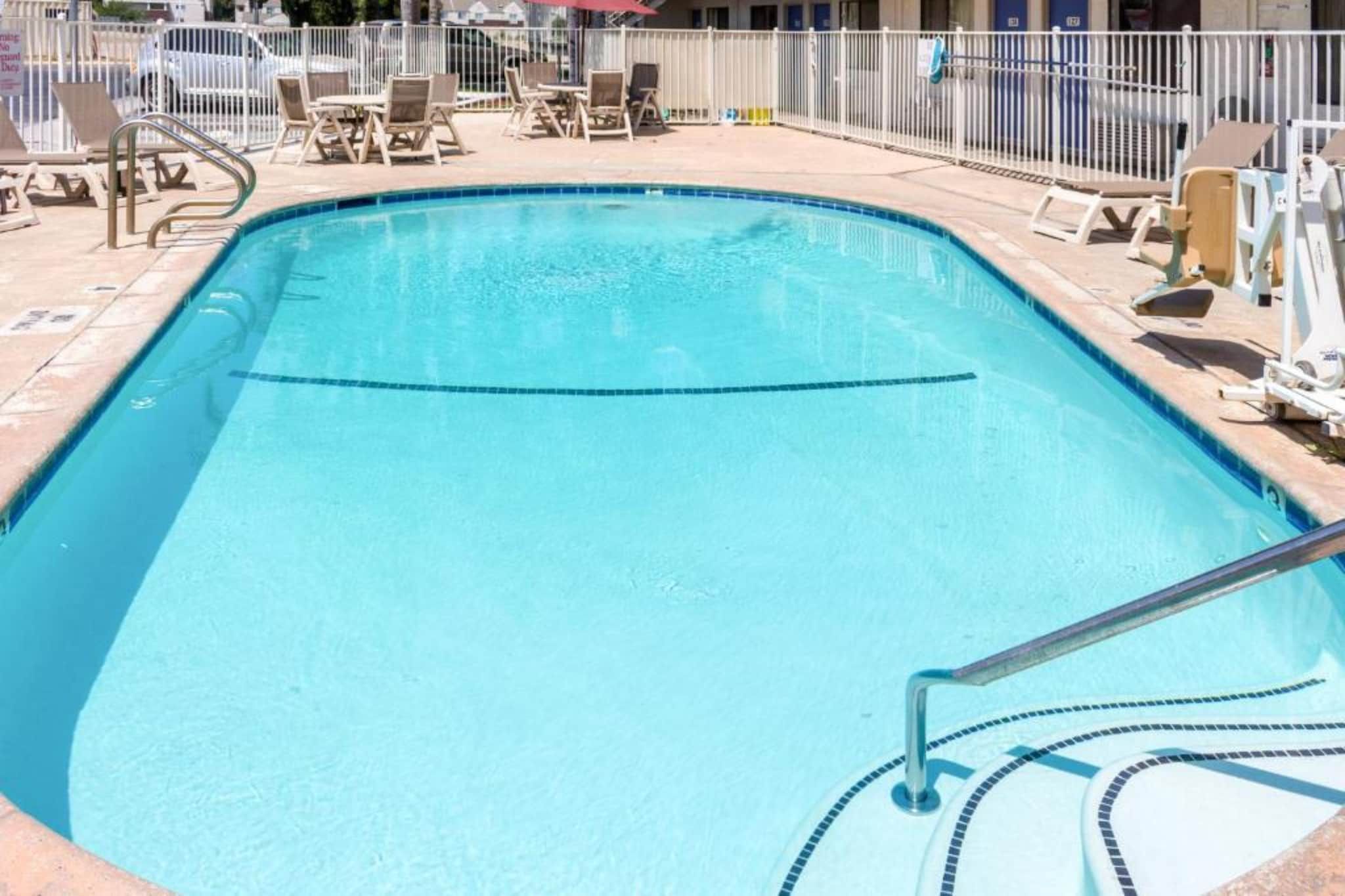 Et rektangulært swimmingpool med en klar blå vandlinje, omgivet af et hvidt hegn.