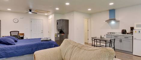 A compact living space with a bed, a sofa, a kitchenette, and a ceiling fan.