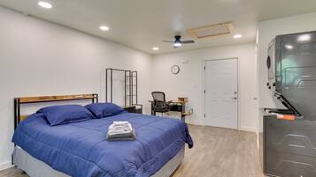 A bedroom with a bed, a desk, a chair, a wardrobe, and a ceiling fan.