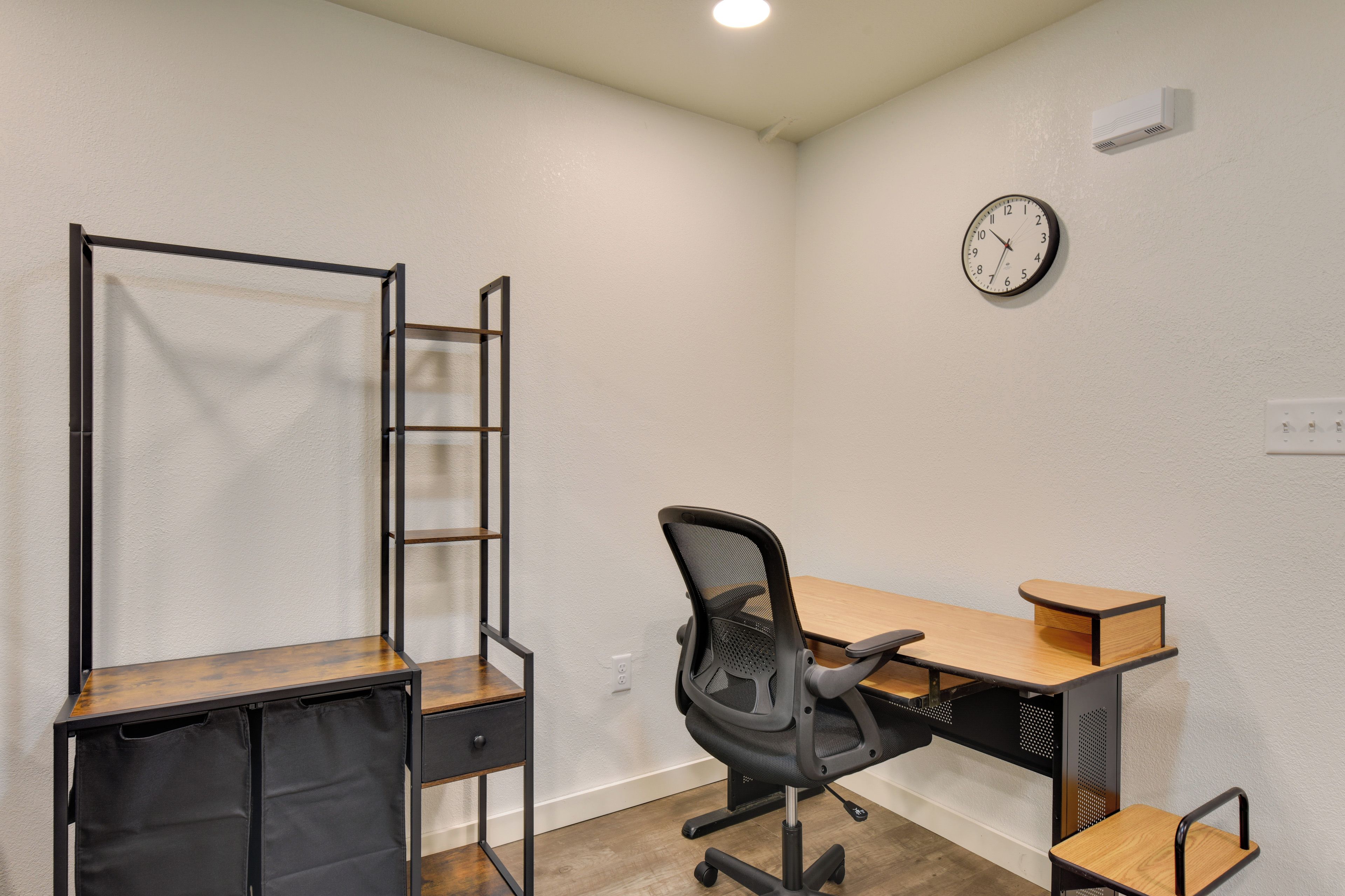 Un espacio de oficina reducido con un escritorio, una silla y un estante en la pared.