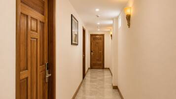 Un pasillo de hotel con puertas de madera, suelo de baldosas e iluminación empotrada.