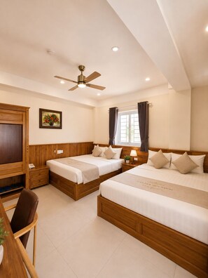 A hotel room with two beds, a ceiling fan, a TV, and a window with curtains.