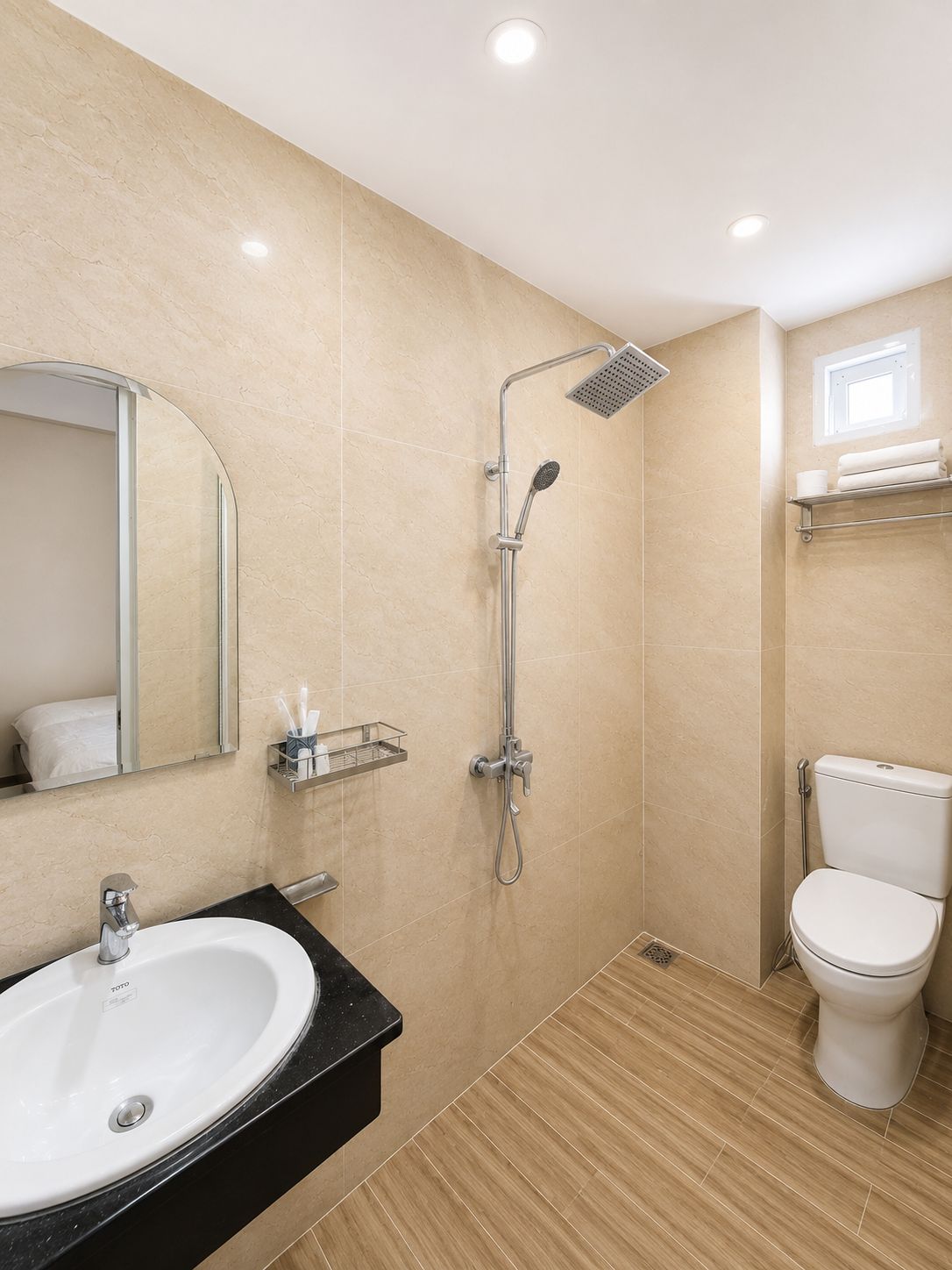 A modern bathroom with a sink, mirror, shower, and toilet.