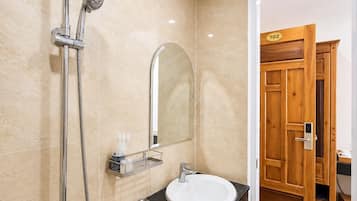 Un baño moderno con ducha, lavamanos y espejo.