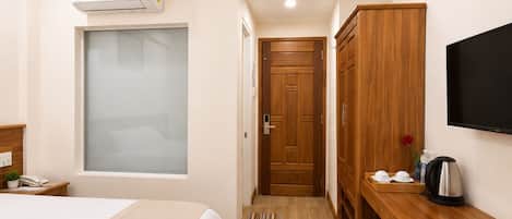 Una habitación de hotel con cama, escritorio, televisor y armario.