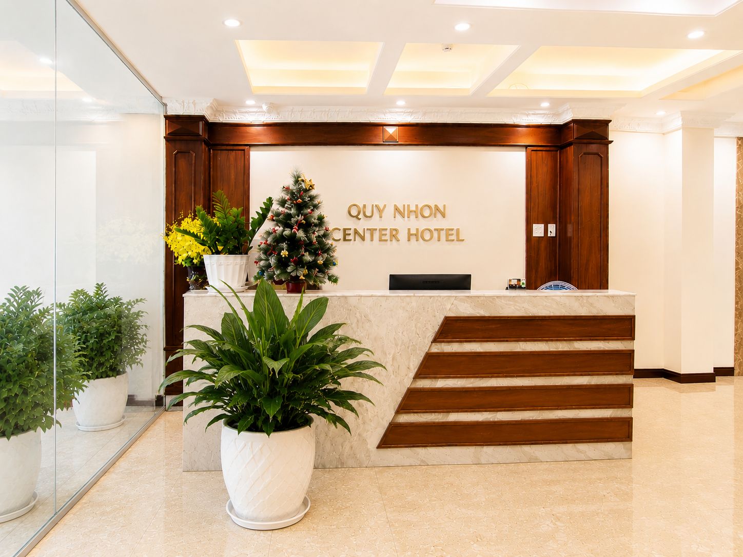 Balcão de recepção com árvore de Natal e plantas em vasos.