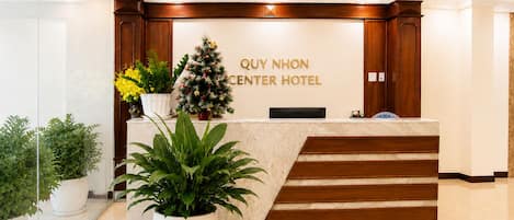 A reception desk with a Christmas tree and potted plants.