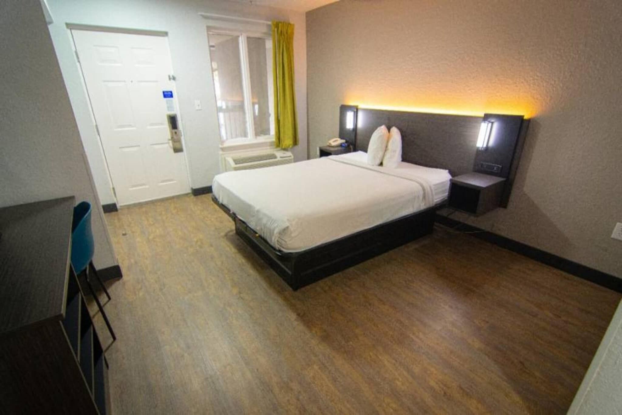 A hotel room with a bed, bedside table, and a desk with a chair.