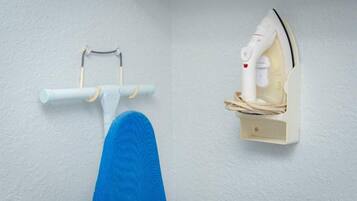 Un rincón de una habitación con una pared blanca, una silla azul y un centro de planchado fijado a la pared.