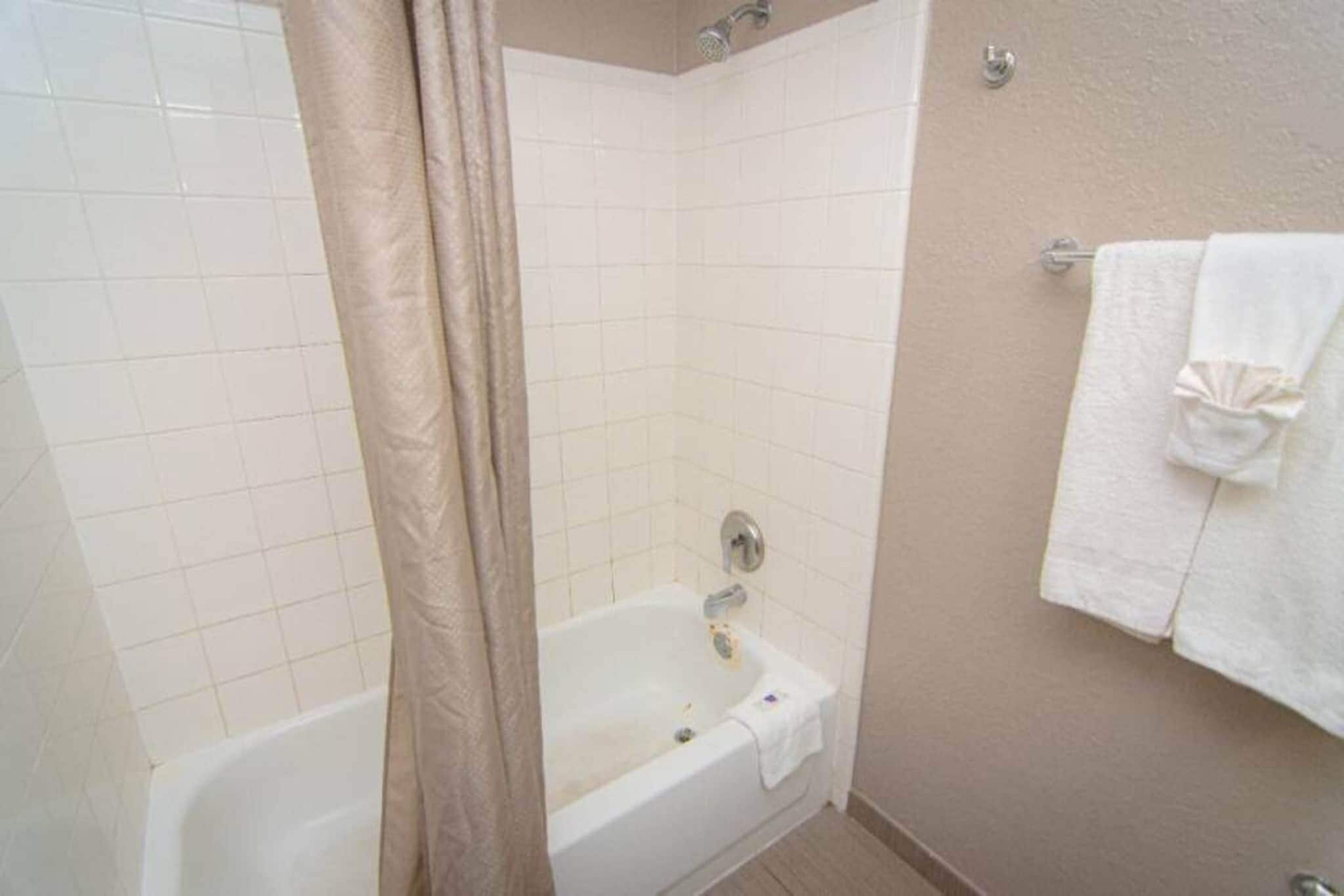 A bathroom with a bathtub, a shower curtain, and a towel rack.