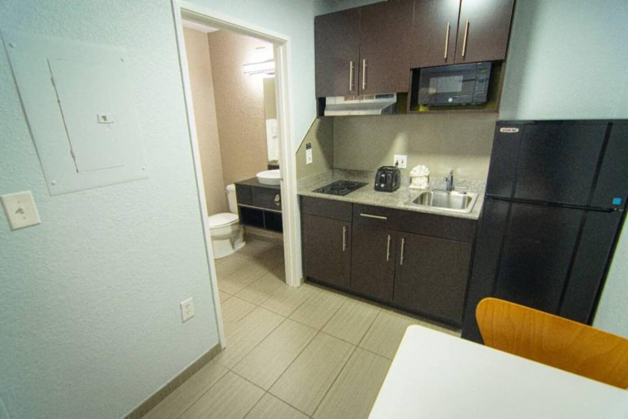 A compact kitchen with dark cabinets, a microwave, a sink, and a refrigerator.