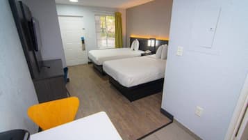 Une chambre d’hôtel avec deux lits, un bureau, une chaise et un téléviseur.