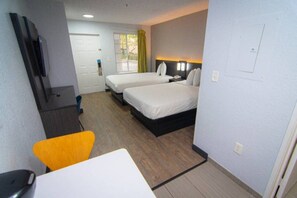 Une chambre d’hôtel avec deux lits, un bureau, une chaise et un téléviseur.