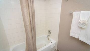 A bathroom with a bathtub, a shower curtain, and a towel rack.