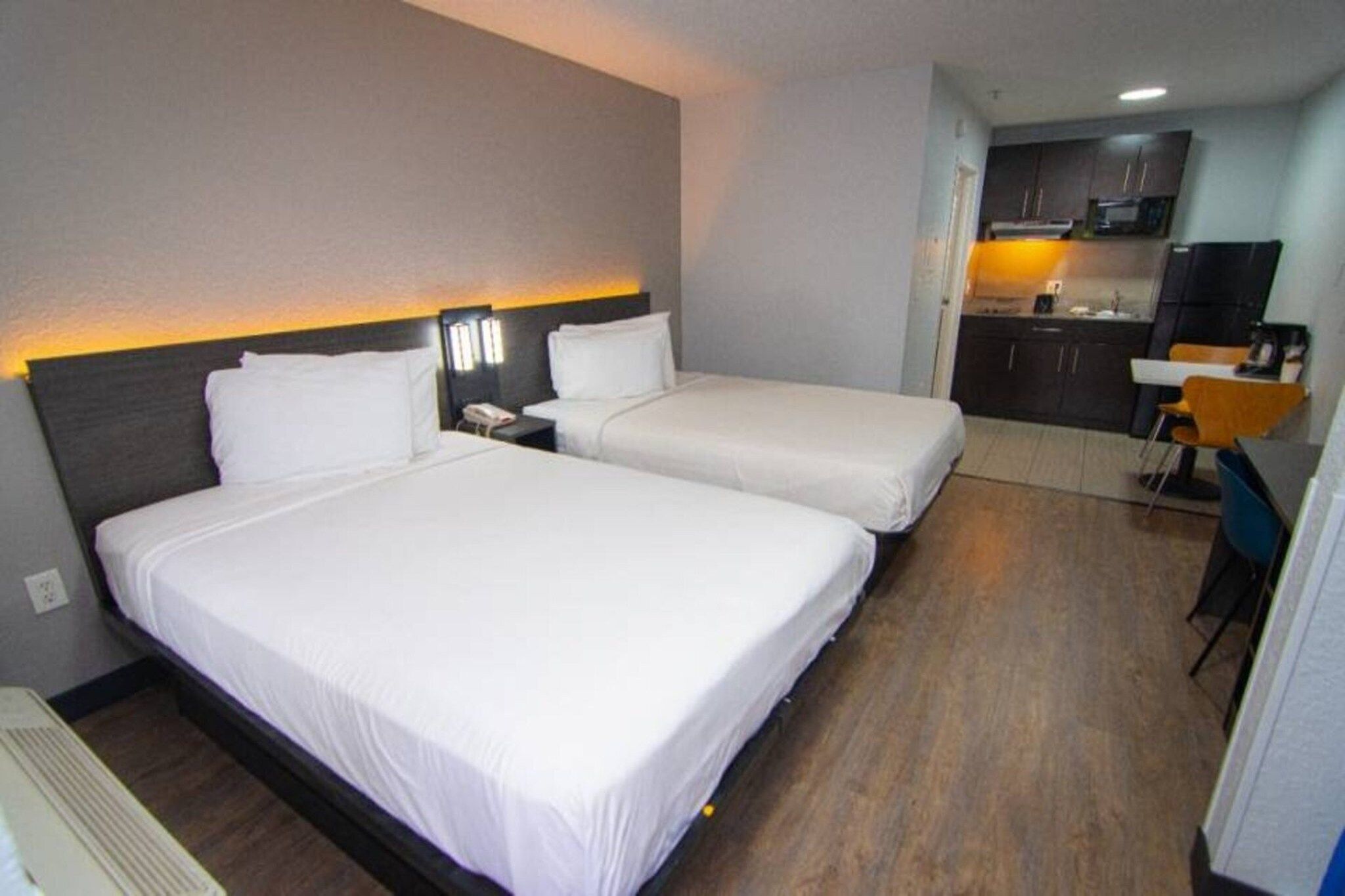 Habitación de hotel con dos camas, un escritorio y kitchenette.