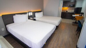 Habitación de hotel con dos camas, un escritorio y kitchenette.