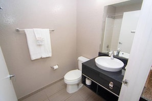 A bathroom with a toilet, sink, and mirror. - 2 Queen Beds|ADA|Roll-In Shower,Nsmk (Coral Springs)