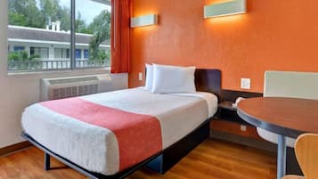 Una habitación de hotel con una cama, una mesa y un ventanal.