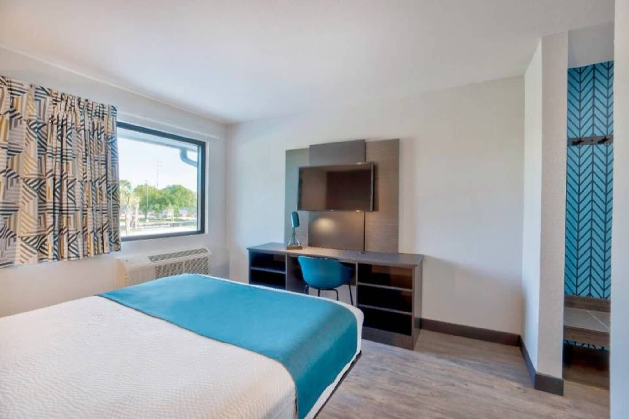 Een hotelkamer met een bed, een bureau, een stoel en een televisie.