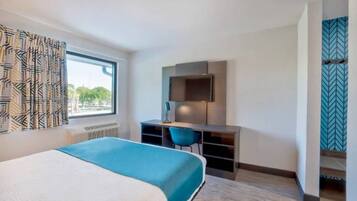 Een hotelkamer met een bed, een bureau, een stoel en een televisie.