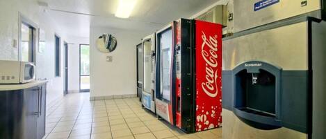 A kitchen area with a microwave, a refrigerator, and a Coca-Cola vending machine.