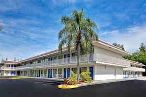 Motel amb una estructura de dues plantes, zona de pàrquing coberta i una palmera al davant.