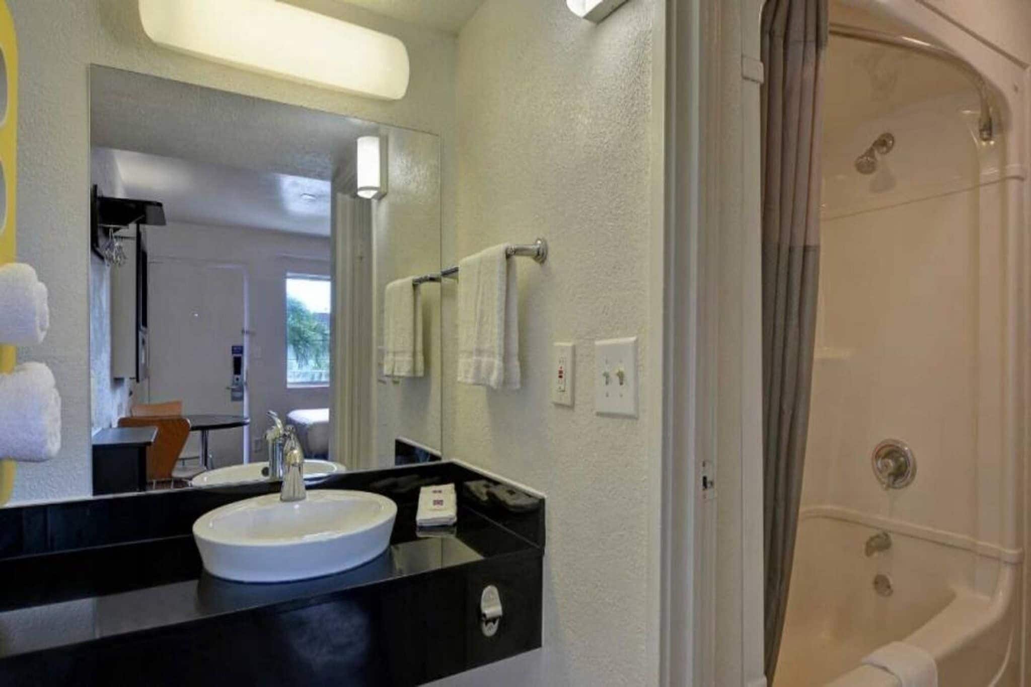 Un baño con lavamanos blanco, un espejo y una ducha.