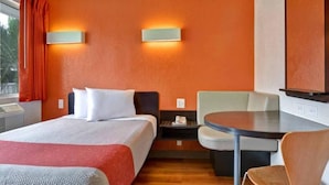 Une chambre d’hôtel avec un lit, un bureau, une chaise et une petite table.