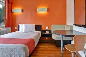 Habitació d'hotel amb un llit, un escriptori, una cadira i una taula petita.