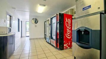 Een kitchenette met een magnetron, een koelkast en een Coca-Cola automaat.