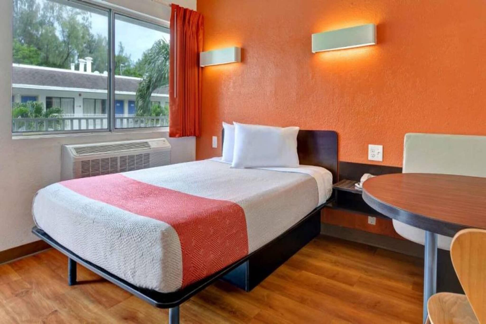 Una habitación de hotel con una cama, una mesa y un ventanal.