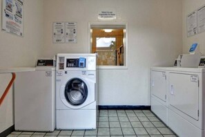 Ett tvättrum med en tvättmaskin med frontmatning, en torktumlare och en skylt som anger att motellet inte ansvarar för föremål som lämnas obevakade.