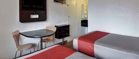A room with two beds, a desk, and a chair.