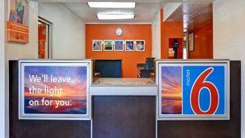 Een receptiebalie van een motel met een bord waarop staat: 'We houden het licht voor u aan'.