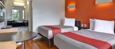 A hotel room with two beds, a dining table, and a kitchenette.