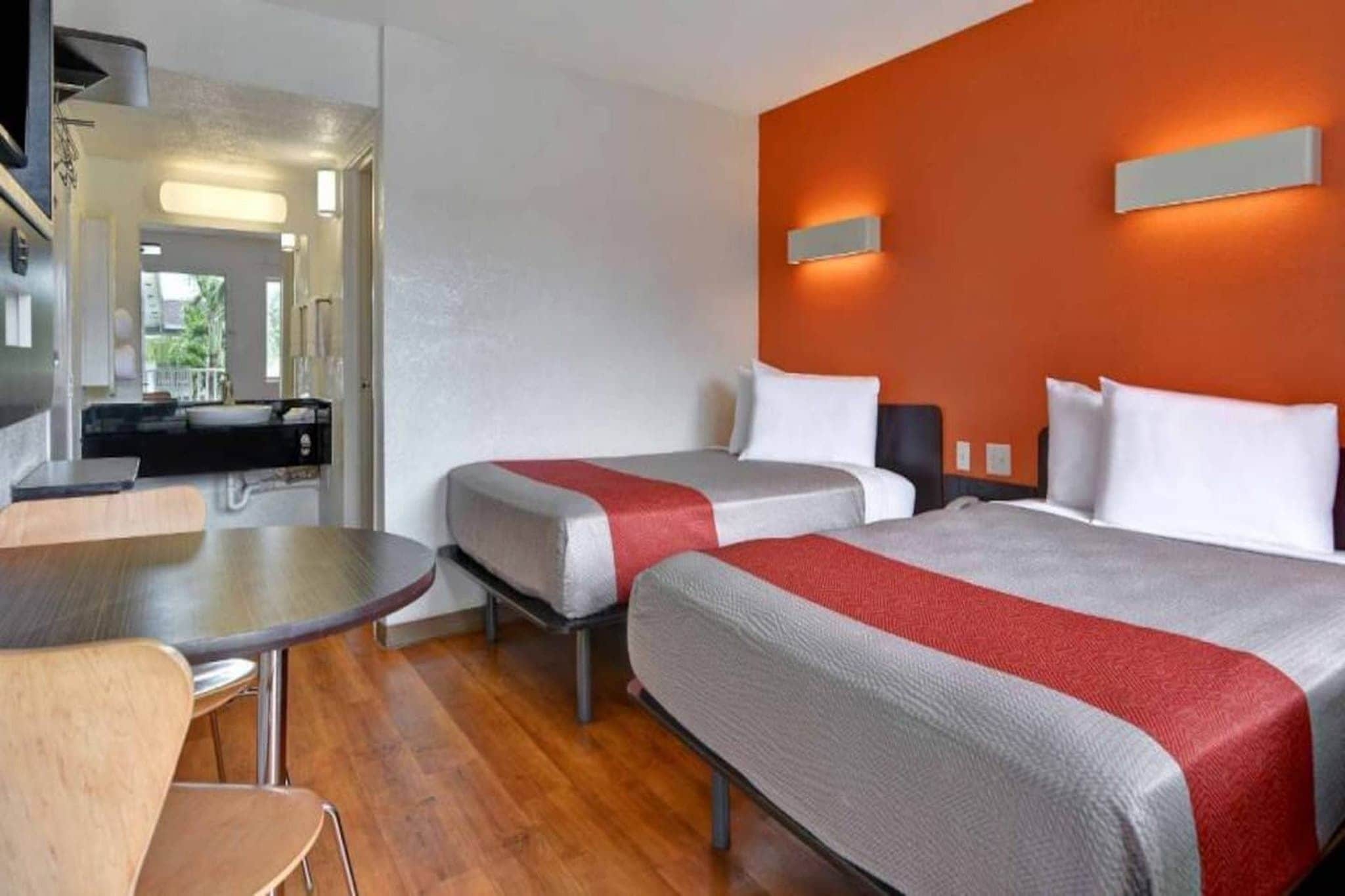 Een hotelkamer met twee bedden, een eettafel en een kitchenette.