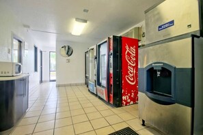 Un coin cuisine équipé d’un four à micro-ondes, d’un réfrigérateur et d’un distributeur automatique de boissons Coca-Cola.