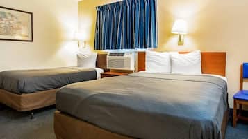 Ein Hotelzimmer mit zwei Betten, einem Fenster mit Vorhängen, einer Klimaanlage und einer Lampe.