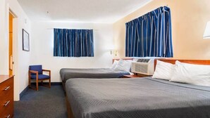 Een hotelkamer met twee bedden, een stoel, een bureau en een raam met gordijnen.