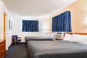 Ett hotellrum med två sängar, en stol, ett skrivbord och ett fönster med gardiner.