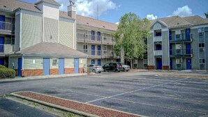 Een parkeerplaats met een rij motelgebouwen, elk met een laag structuur en een plat dak.
