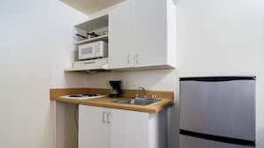 Cozinha compacta equipada com micro-ondas, cafeteira e frigorífico.