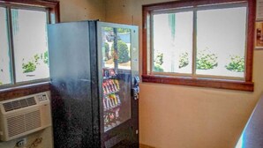 Uma pequena cozinha compacta com geladeira e dispensador de bebidas.