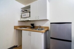 Eine kompakte Küche mit Mikrowelle, Kaffeemaschine und Kühlschrank.