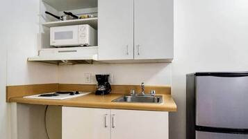 A compact kitchenette with a microwave, a coffee maker, and a sink.
