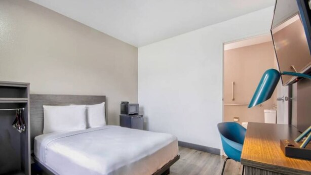 A hotel room with a bed, a desk, a chair, a wardrobe, and a mirror. - ADA Cozy Full Bed Pool Access (Austin TX)