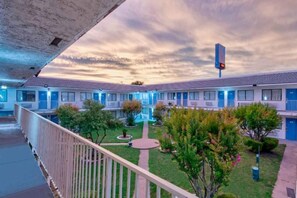 Un motel con un patio central, varias habitaciones con puertas azules y un sendero peatonal.