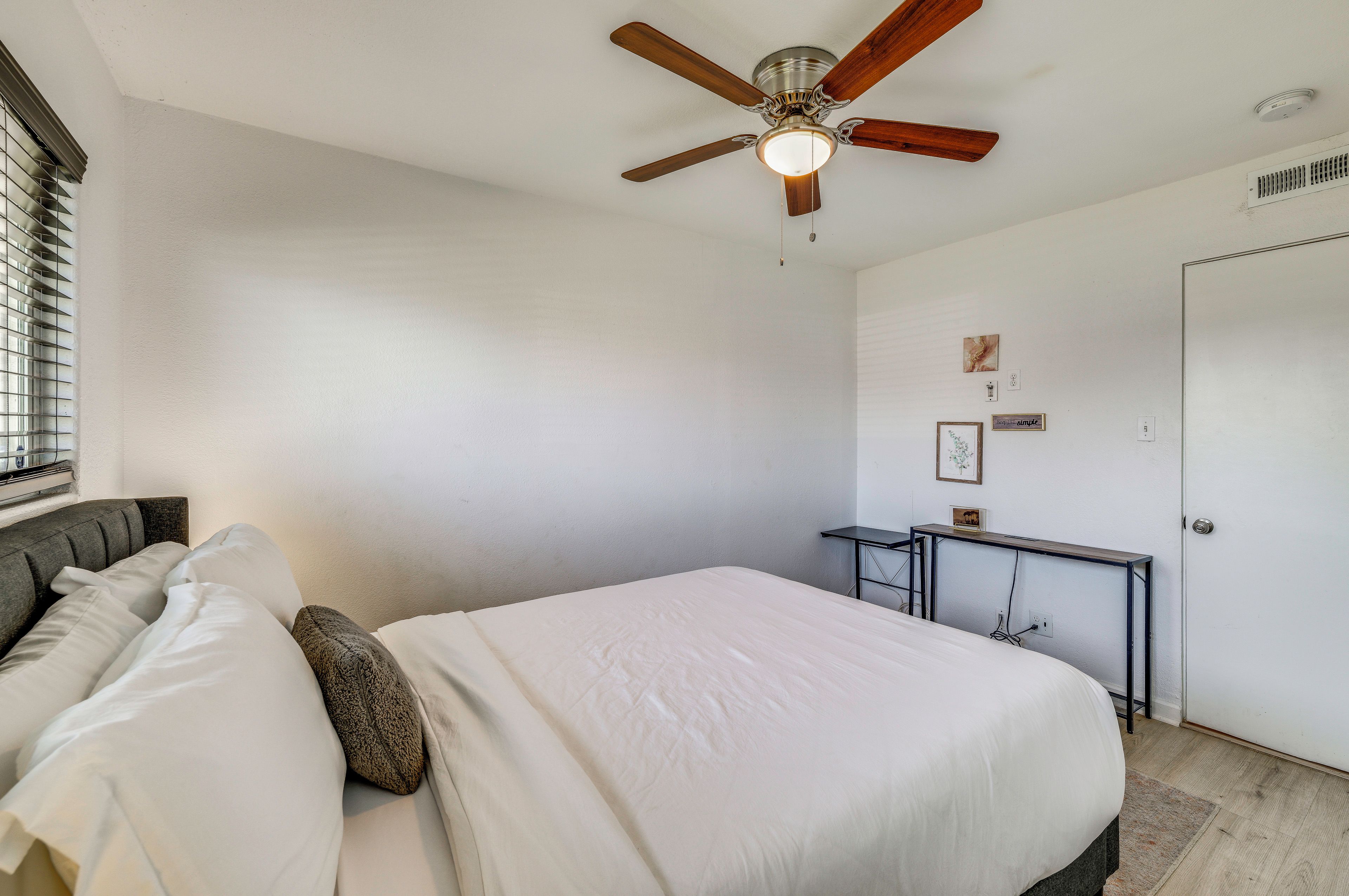 A bedroom with a bed, a desk, and a ceiling fan.