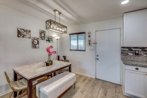 A dining area with a marble table, bench, and chairs. There is a wall-mounted light fixture above the table. - 5 Mi to Empire Polo Club! Poolside Group Getaway (Indio)