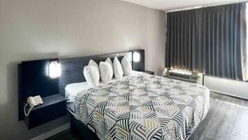Une chambre d’hôtel avec un lit, une table de chevet et une fenêtre avec des rideaux.